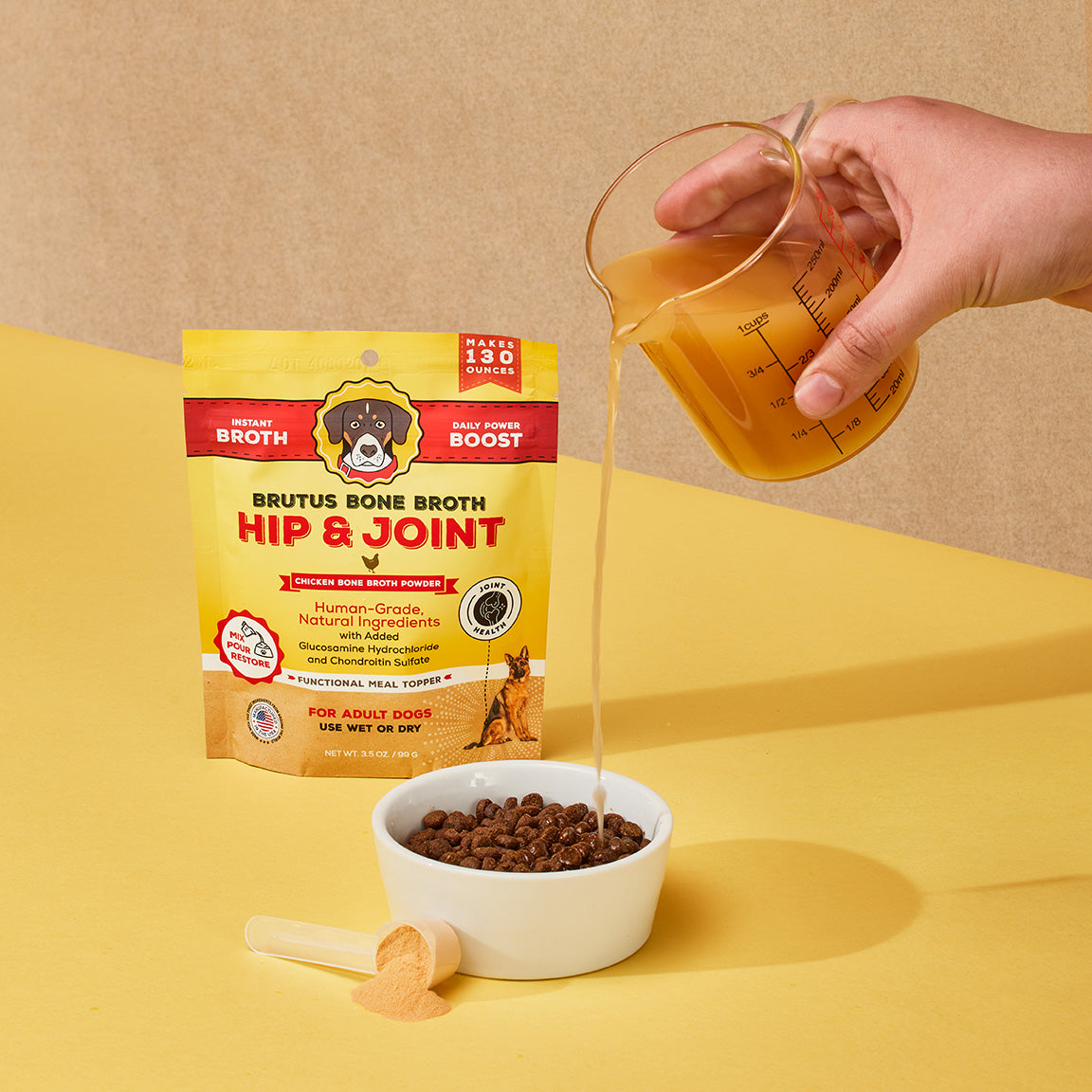 Brutus Bone Broth Hip & Joint Chicken Bone Broth Powder. Pouring liquid bone broth into bowl of kibble