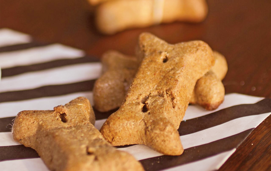 Close-up of bone-shaped peanut butter dog cookies showcasing golden-brown texture on black-and-white striped paper