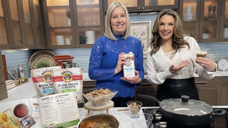 Co-founder Sue Delegan on a cooking show with BRUTUS BONE BROTH BISCUITS packaging, a bone-broth carton, and a recipe card on the counter.
