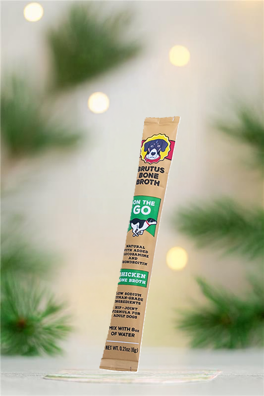 Chicken Brutus Broth on the Go Stick with pine tree branches and twinkly lights in the background