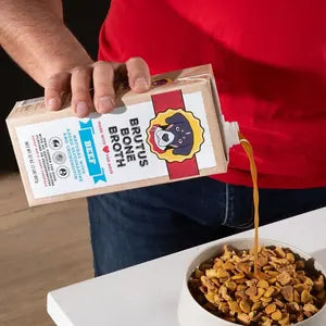 Pouring Brutus Bone Broth over a bowl of kibble